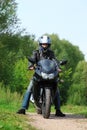 Motorcyclist standing on country road