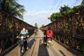 Motorcyclists and Cyclists crossing old bridge across Mekong River