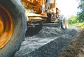 Motorgrader are adjusted to smooth the crushed rock for road construction in the next step. Royalty Free Stock Photo