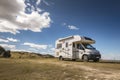 Motorhome parked on rural dirt road with trees and fields under a blue sky Royalty Free Stock Photo