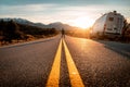 Motorhome and the silhouette of a man standing in the middle of an asphalt road during the sunset