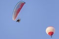 Motorized paraglider and hot air balloon against a beautiful blue sky