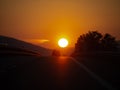 Motorway sunset, with holidaymaker cars returning from vacation, holiday. Homeward bound. Genuine image. Large sun. Royalty Free Stock Photo