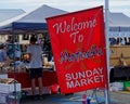 Motueka Sunday market sign in front of market stalls