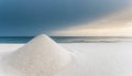 A mound of white sand in front of blue ocean at sunset