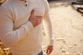 Moung man stands on park alley and holds to his sternum