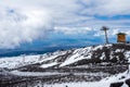 Mount Etna national park in winter. View from volcano crater with black volcanic lava stones and snow under cloudy sky Royalty Free Stock Photo
