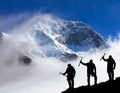 Mount Makalu with clouds and silhouette of three hikers