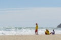 Two young surf lifeguards and a boy sit on hazy beach