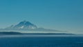 Mount Rainier with a dusting of snow viewed from the water with a blue sky