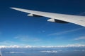 Mountain and airplane wing landscape viewed from aircraft window with white cloud and golden sunlight Royalty Free Stock Photo