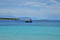 Single boat anchored in the middle ocean with mountain and island backdrops