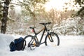 Mountain Bike with Backpack and Helmet in Beautiful Winter Forest Lit by the Sun. Adventure and Travel Concept. Royalty Free Stock Photo