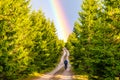 Mountain bike cycling after rain. Woman rides towards bright rainbow through forest country road. Outdoor sport theme Royalty Free Stock Photo