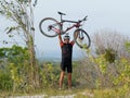 A mountain biker is happy holding his bike above his head while standing on top of a mountain. Royalty Free Stock Photo