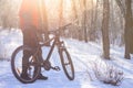 Mountain Biker with his Bike on the Snowy Trail in the Beautiful Winter Forest Lit by Sun Royalty Free Stock Photo