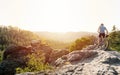 Mountain biker holding his bike on a rough cliff terrain on a sunset