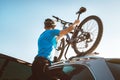 Mountain biker man take of his bike fron the car roof