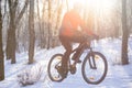 Mountain Biker Riding Bike on the Snowy Trail in the Beautiful Winter Forest Lit by Sun Royalty Free Stock Photo
