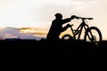 Mountain biker standing on top of a mountain with a bicycle, a beautiful sunset. Silhouette of a cyclist