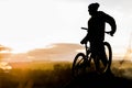 Mountain biker standing on top of a mountain with a bicycle, a beautiful sunset. Silhouette of a cyclist