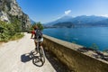 Mountain biking at sunrise woman over Lake Garda on path Sentiero della Ponale, Riva del Garda, Italy