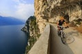 Mountain biking at sunrise woman over Lake Garda on path Sentiero della Ponale, Riva del Garda, Italy