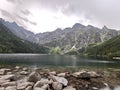 Mountain blue lake among the snow-covered rocks of the Polish Tatras in the summer, active recreation of the tourist