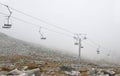Mountain cableway chairlift in clouds and fog