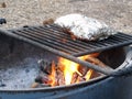 Mountain Camp Fire Cooking Foil Dinners on Grate Over Hot Pit
