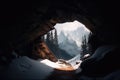 mountain cave with snow-covered entrance, surrounded by majestic snowy peaks