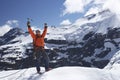 Mountain climber with arms raised on top of snowy peak Royalty Free Stock Photo