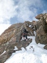 Mountain climber and backcountry skier rappelling off a high alpine rocky and snow peak