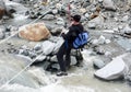 Mountain climber crossing a wild mountain river on a tyrolienne rope construction high up in the air