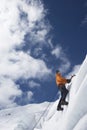 Mountain Climber Going Up Snowy Slope With Axes