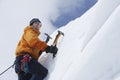 Mountain Climber Going Up Snowy Slope With Axes