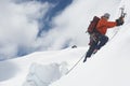 Mountain Climber Going Up Snowy Slope With Axes
