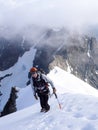 Mountain climber on a steep and narrow snow ridge leading to a high peak in the Swiss Alps Royalty Free Stock Photo