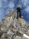 Mountain climber rappelling off a steep and narrow rock ridge leading down from a high peak in the Swiss Alps Royalty Free Stock Photo