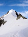 Mountain climbers on a steep and narrow snow ridge leading to a high peak in the Swiss Alps Royalty Free Stock Photo