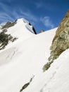 Mountain climbers on a steep and narrow snow ridge leading to a high peak in the Swiss Alps Royalty Free Stock Photo