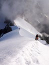 Mountain climbers on a steep and narrow snow ridge leading to a high peak in the Swiss Alps Royalty Free Stock Photo