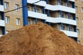 mountain of construction sand in the background of a brick house under construction with blue inserts and no glazed Royalty Free Stock Photo