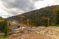 Mountain construction site with multiple cranes. A large construction site in a mountain valley with several yellow tower cranes Royalty Free Stock Photo