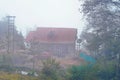 A mountain cottage in a foggy morning. Mist hill and forest in December winter landscape Royalty Free Stock Photo