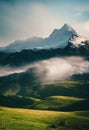 a mountain covered in clouds and green grass with a few trees in the foreground and a few houses in the distance Royalty Free Stock Photo