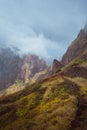 Mountain edge overgrown with verdant grass along the trekking path. Mountain peaks are encase by fog . Xo-Xo Valley