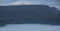 Mountain evening landscape with low clouds in the valley and a steep cliff in the background