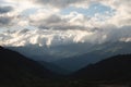 Mountain forest gorge landscape, clouds cling to the tops of high mountains, a glimpse of the sun's rays Royalty Free Stock Photo