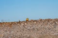 On the mountain of garbage in the dump a big yellow tractor, a lot of sky Royalty Free Stock Photo